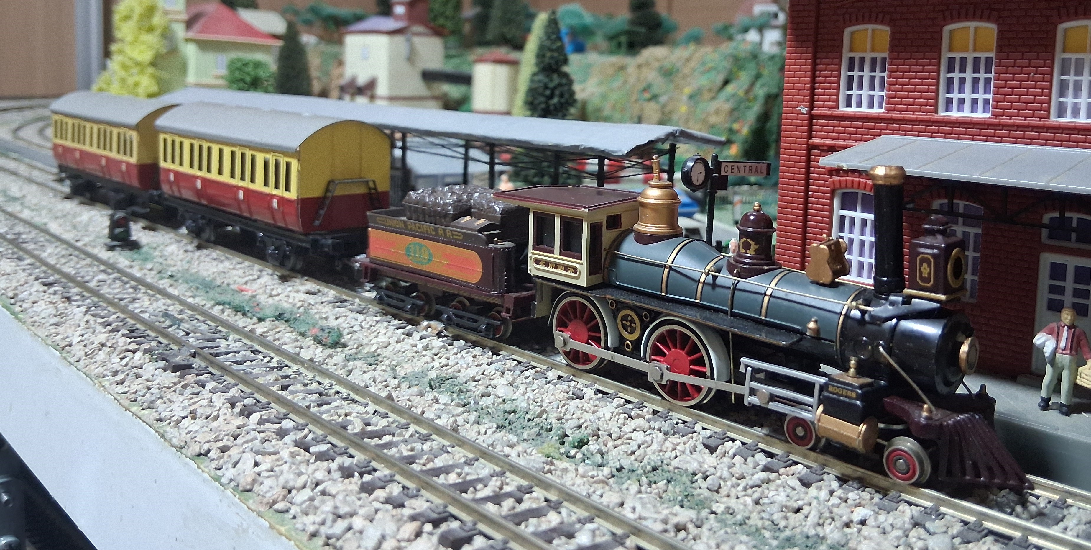 La locomotora histórica estacionada en la maqueta junto a los vagones de pasajeros