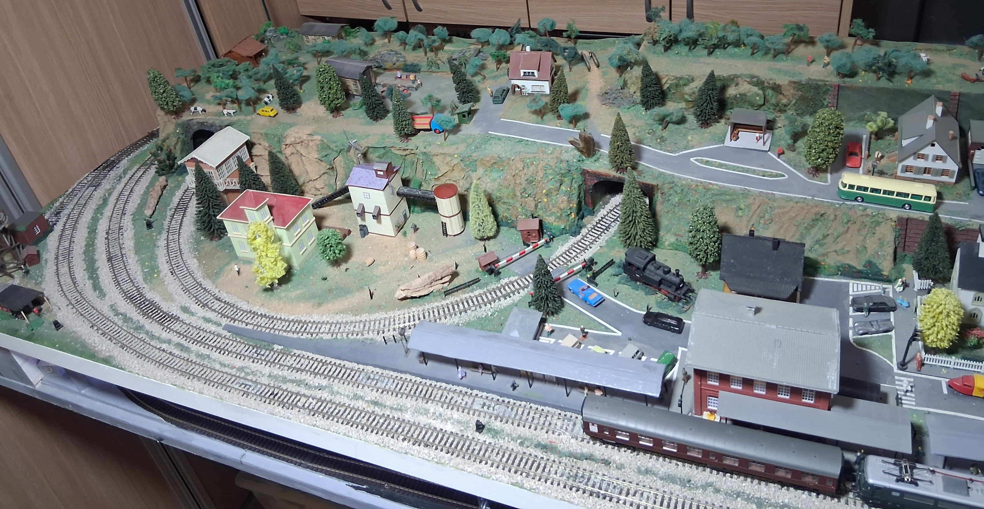 Maqueta de trenes a escala con edificios industriales y túneles