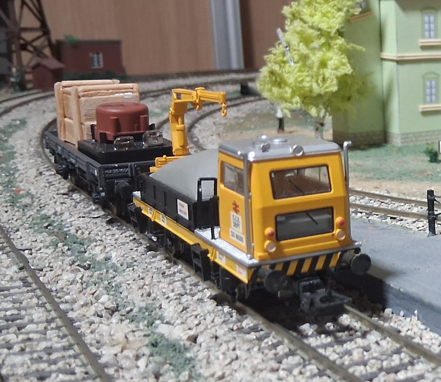 Vehículo de mantenimiento amarillo de British Rail en la vía arrastrando un vagón de suministros